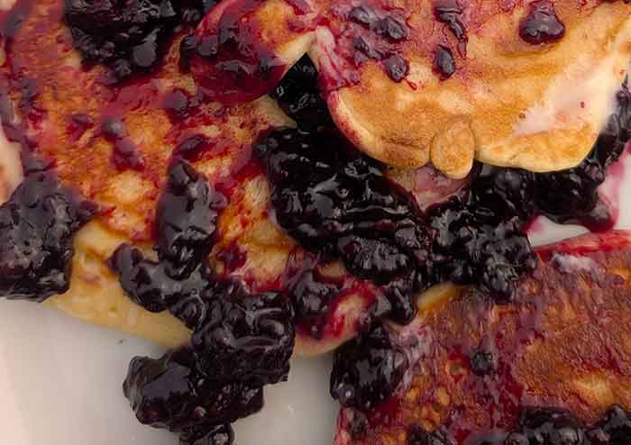Buttermilk pancakes covered with blackberry jam.